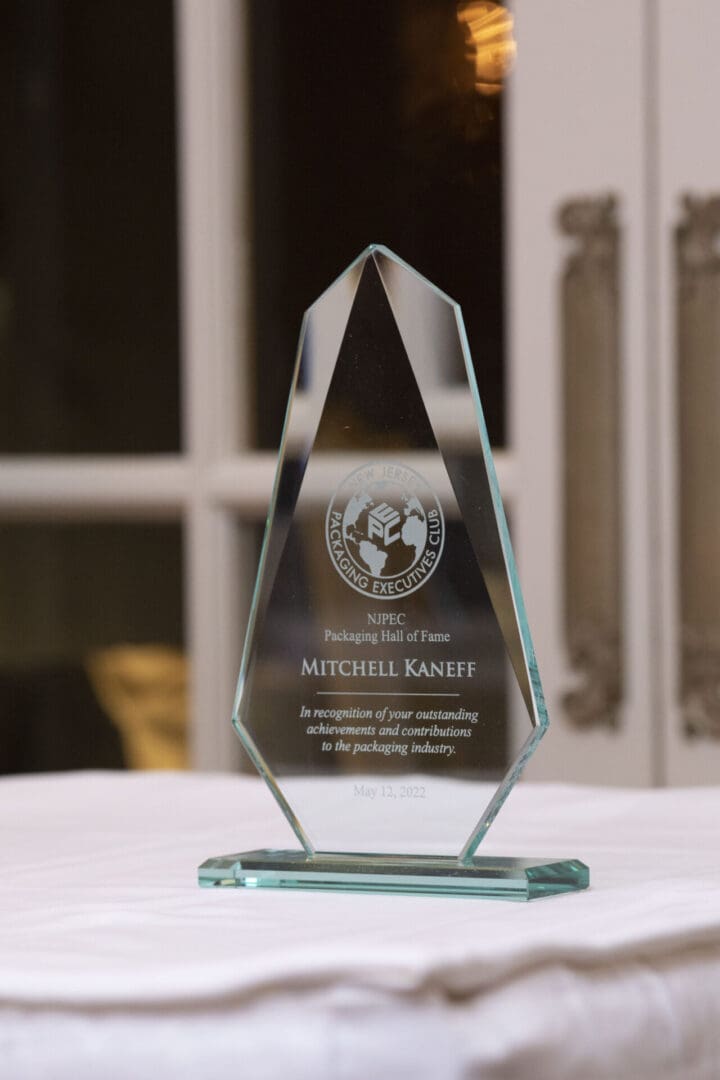 A glass award sits on a table in front of a window.