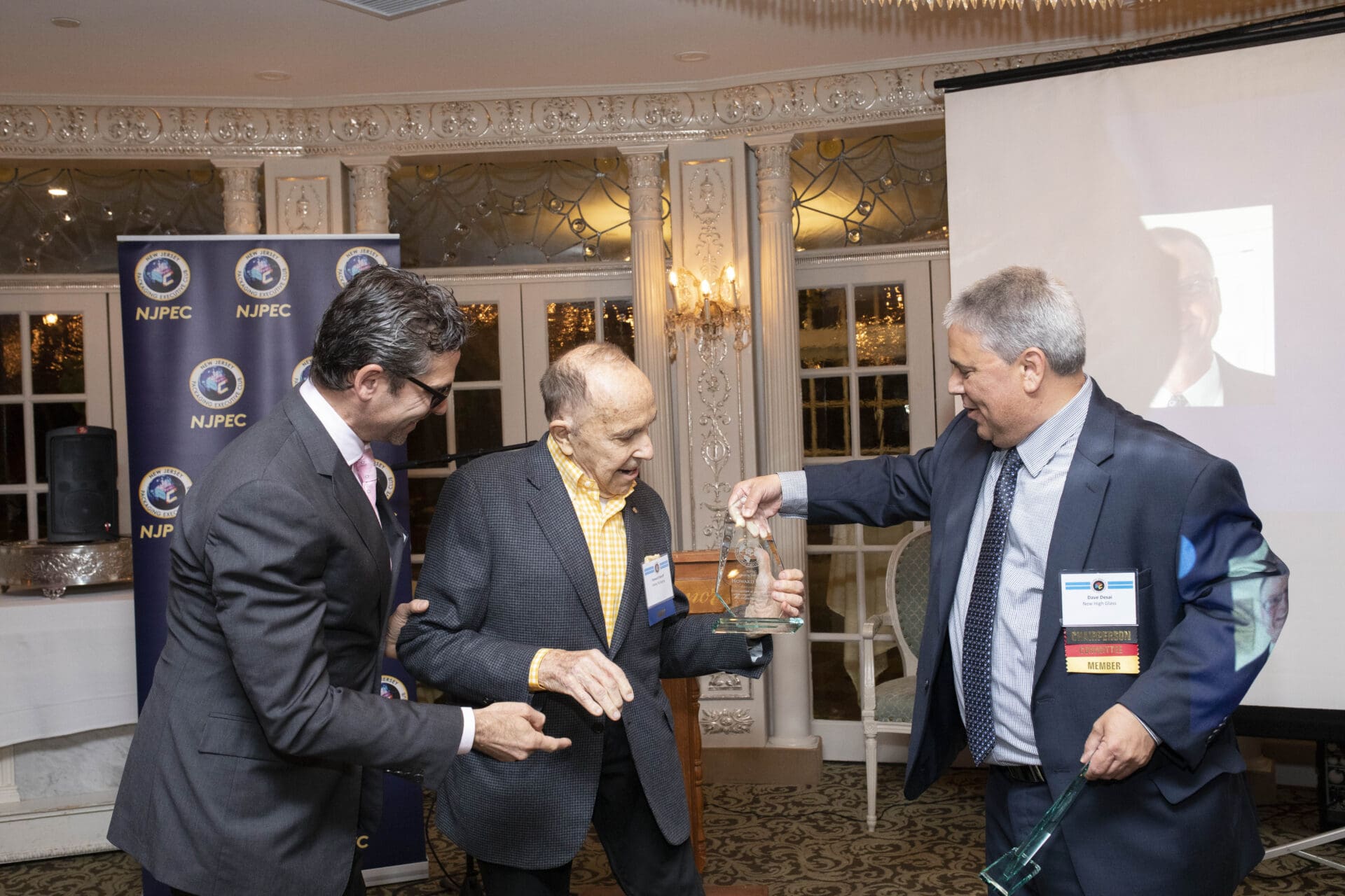 A man in a suit is handing an award to a man in a suit.
