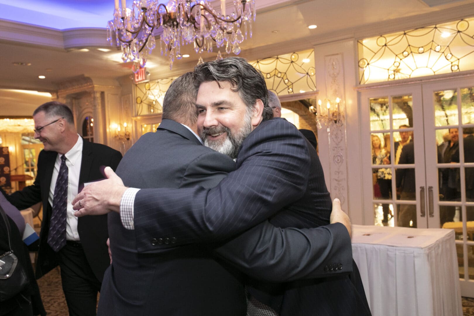 A man is hugging another man at a party.