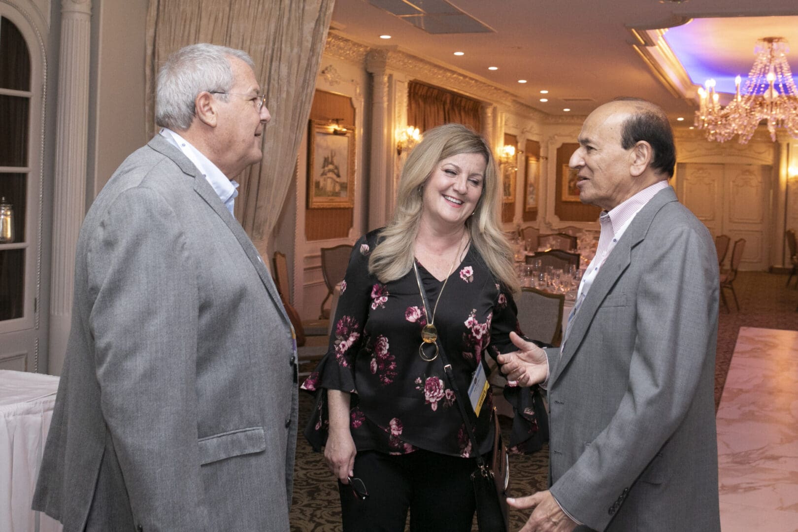 Two men and a woman talking at an event.