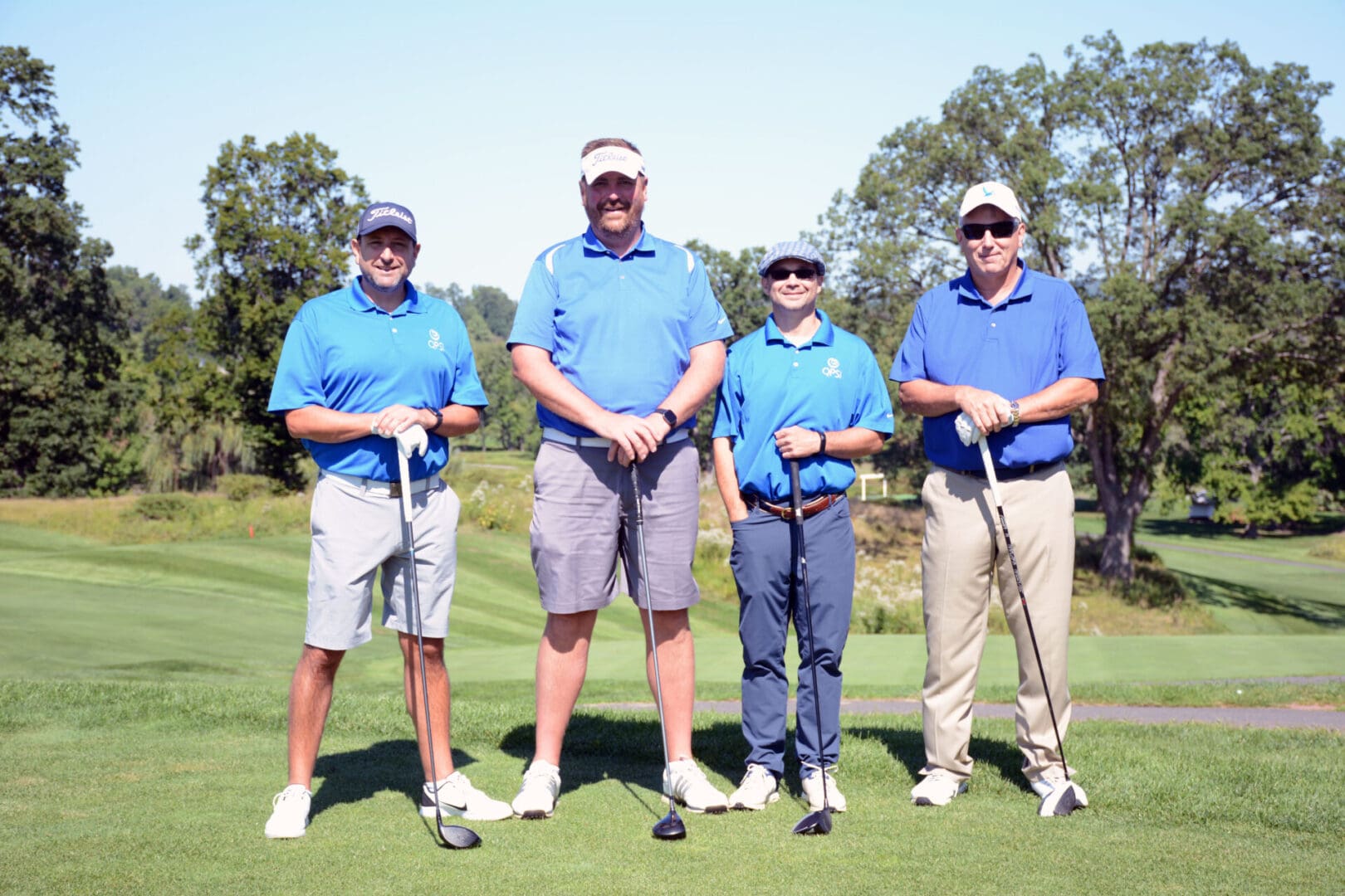 four golfers wearing blue polo shirts