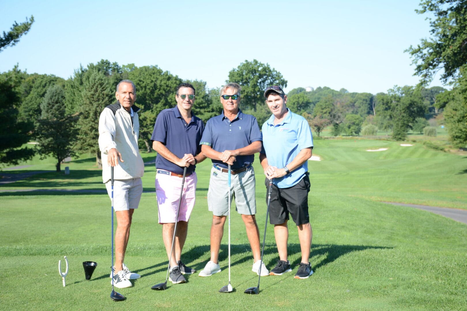 men wearing sunglasses and wearing dark blue polo shirts and holding golf clubs