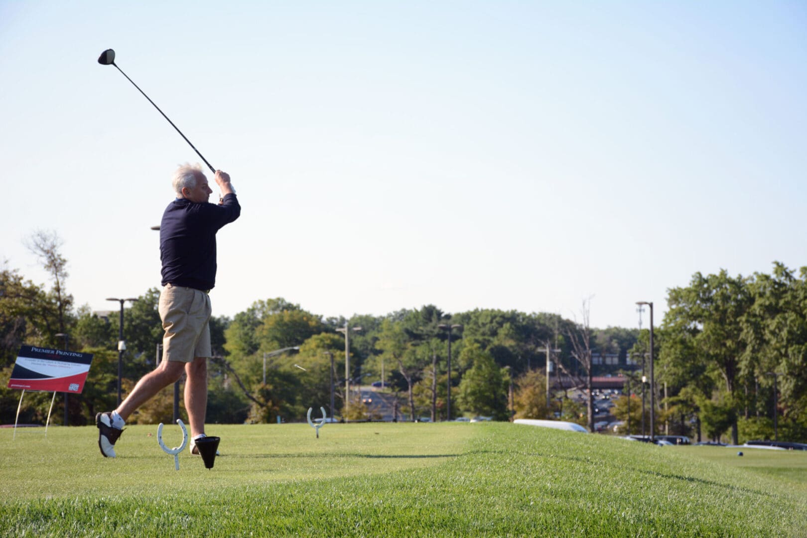 man with white hair wearing black shirt playing golf