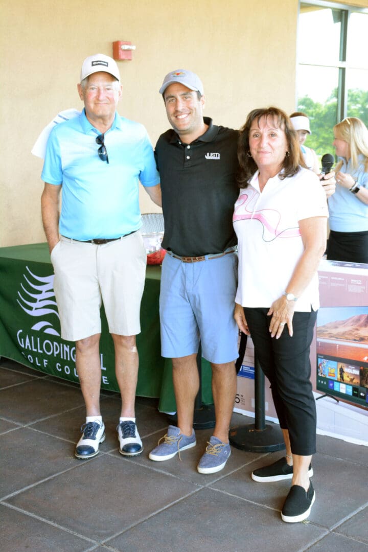 Three people posing for a photo at a golf tournament.