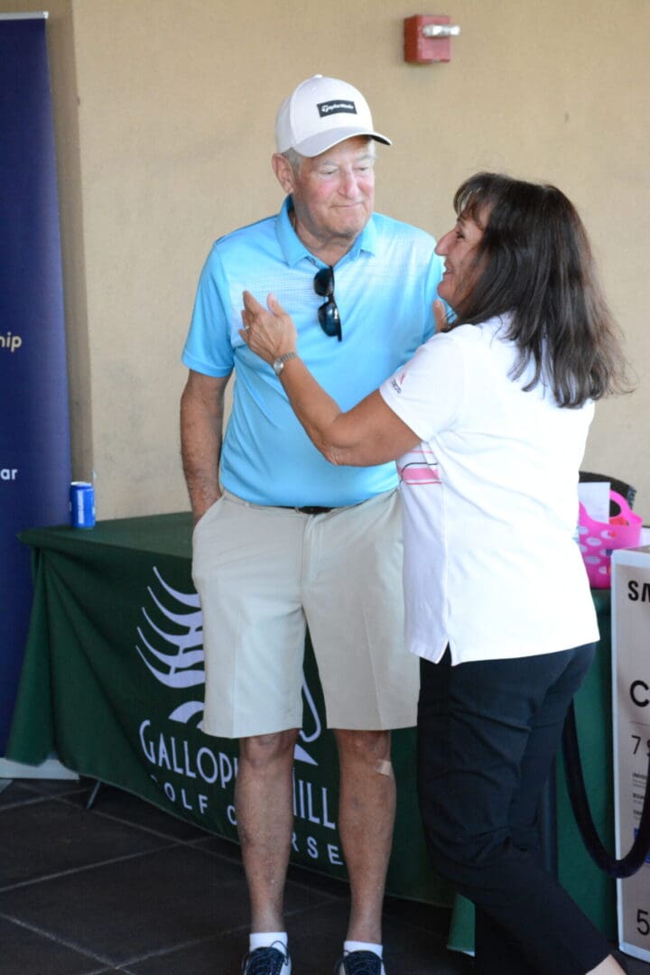 A man and woman standing next to each other at a golf tournament.