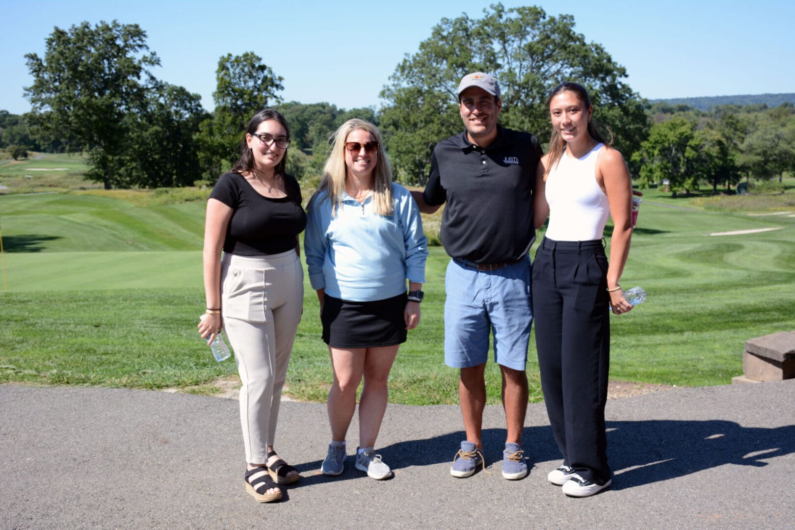 Four people posing for a photo on a golf course.