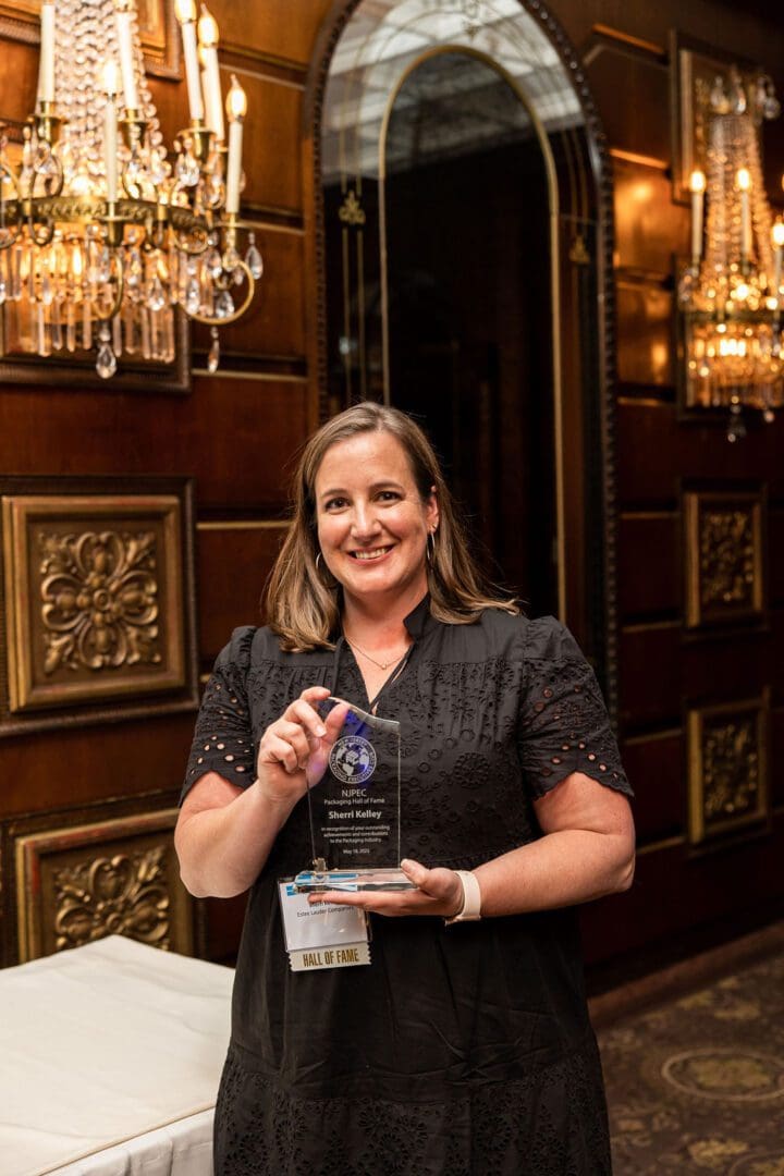 A woman holding an award in front of a chandelier.