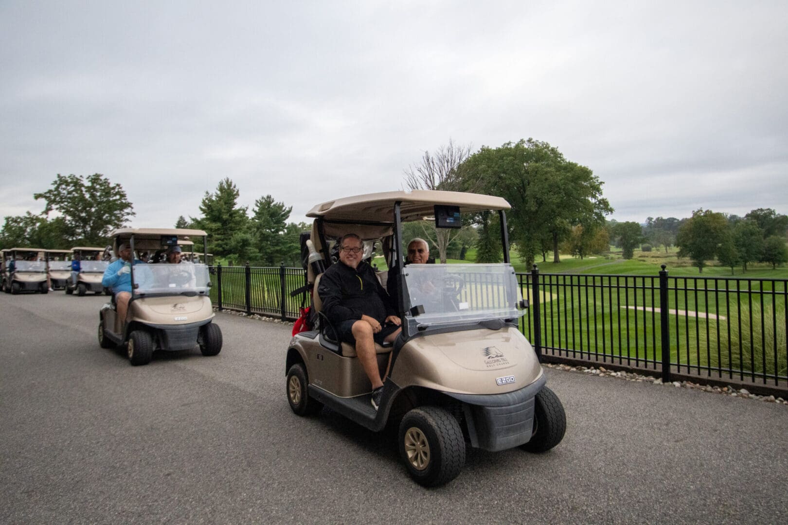 A group of people riding golf carts on a golf course.