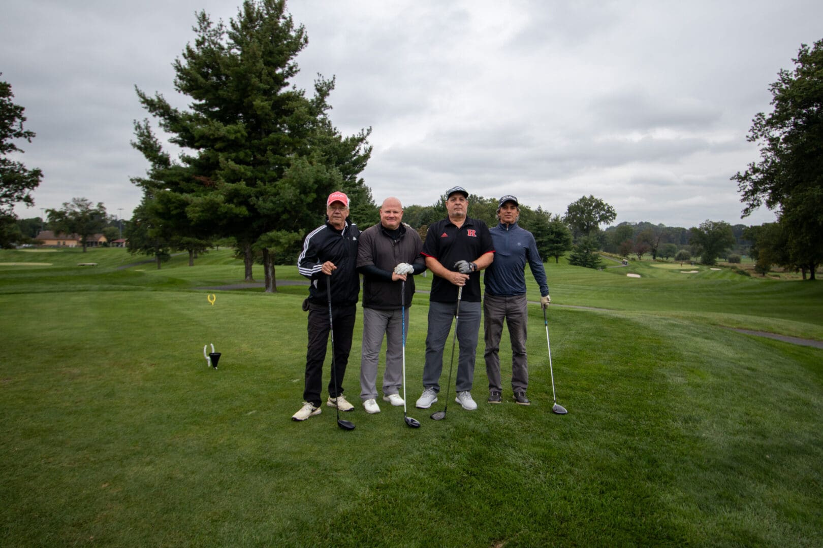 4 men in dark colors on a golf course
