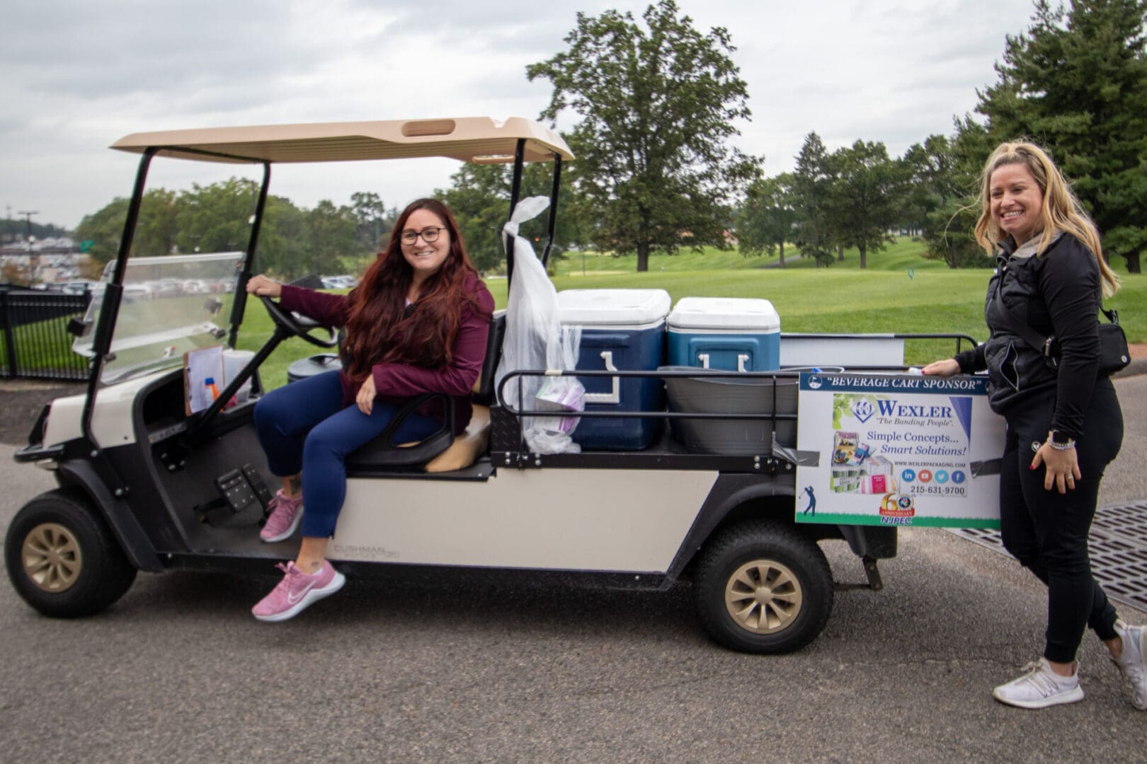 2 women next to a golf cart