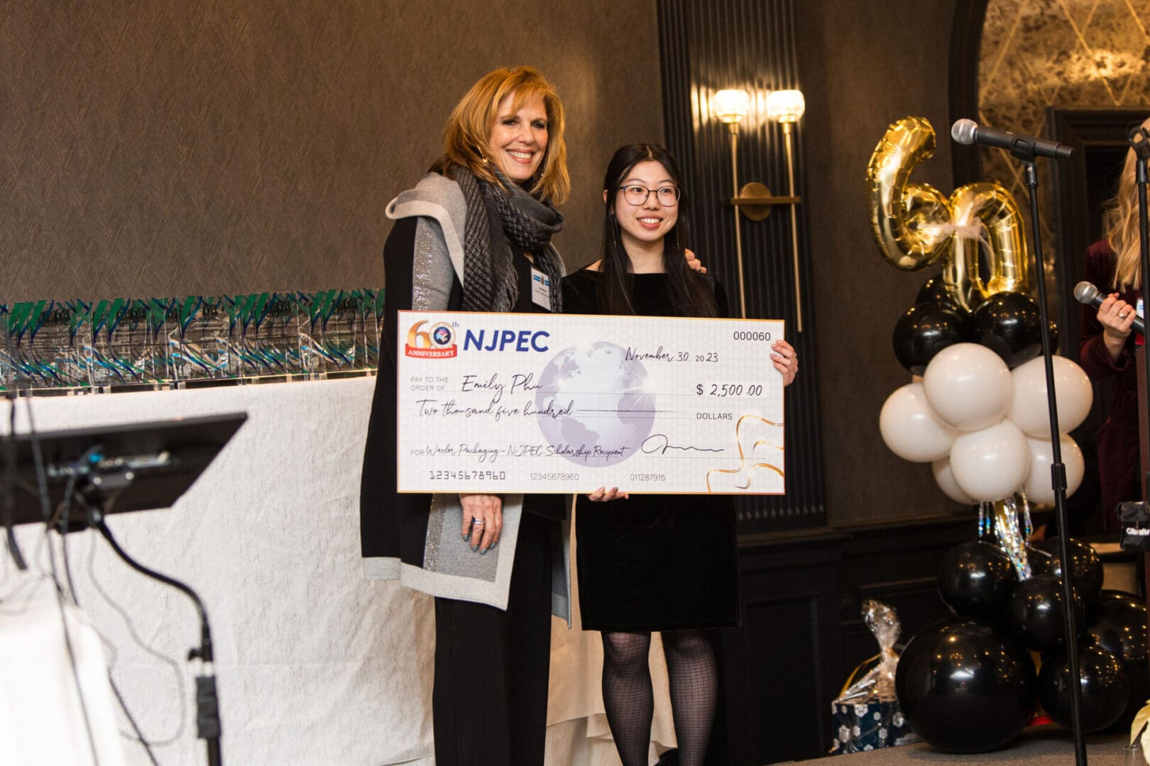 Two women standing next to each other holding a check.