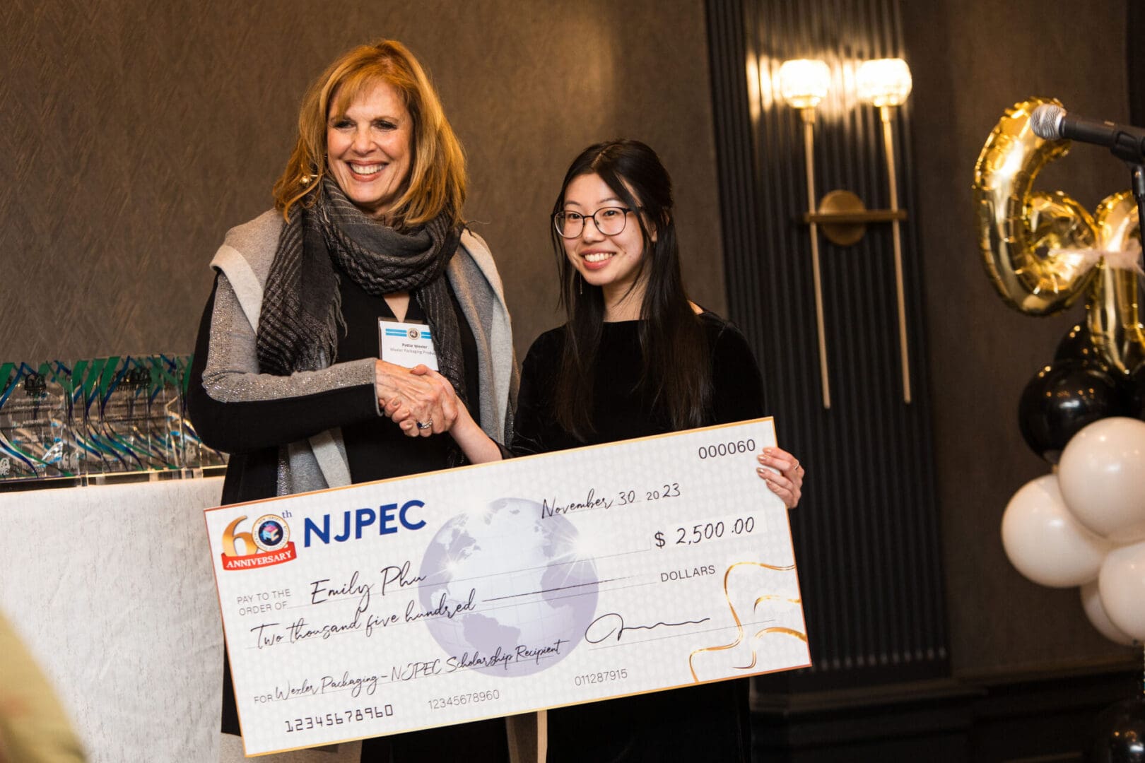 Two women standing next to each other holding a check.