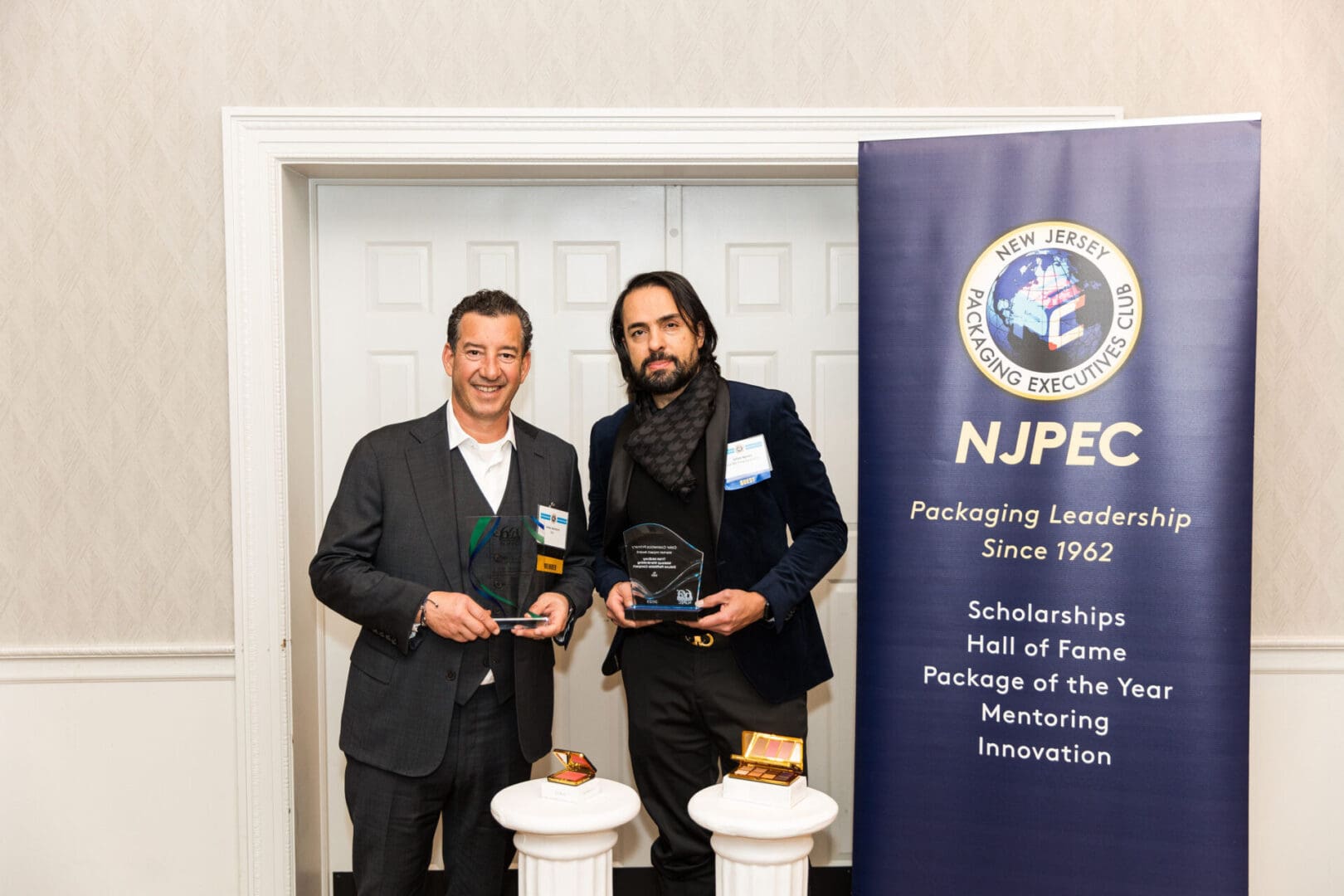 Two men standing next to each other holding awards.