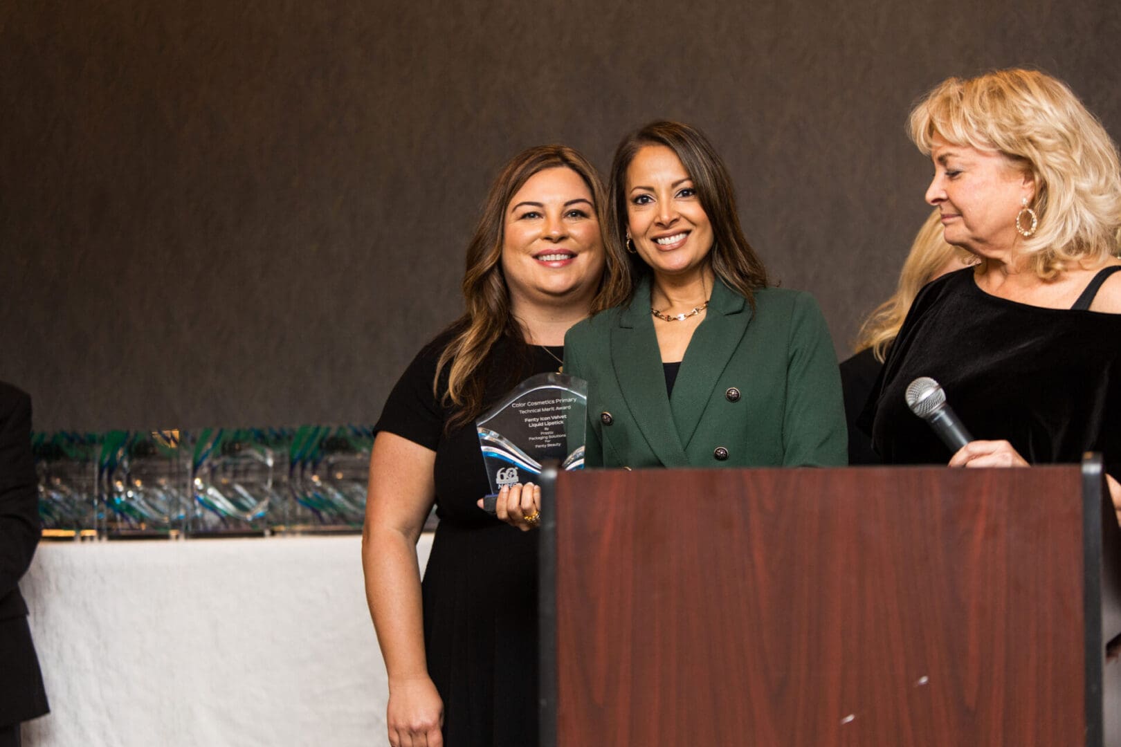 Three women standing at a podium holding an award.