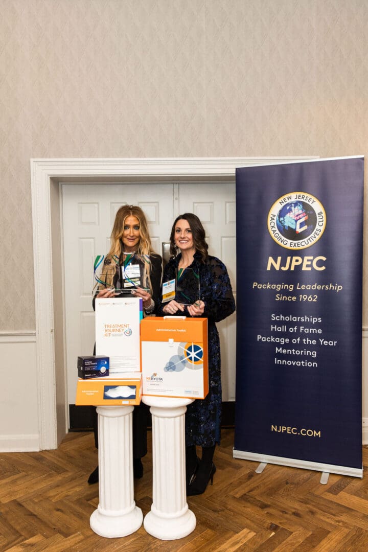 Two women standing in front of a banner with the word nupc.