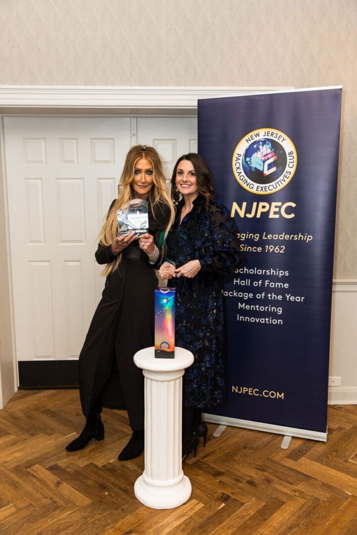 Two women standing in front of a banner with the word npec.