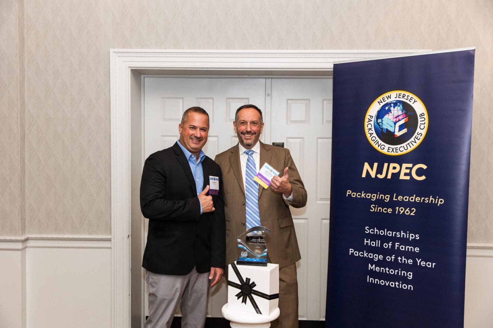 Two men standing in front of a banner with the nppc logo.