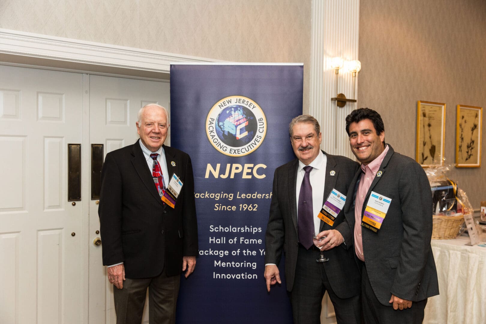 Three men standing in front of a banner with the npcc logo.