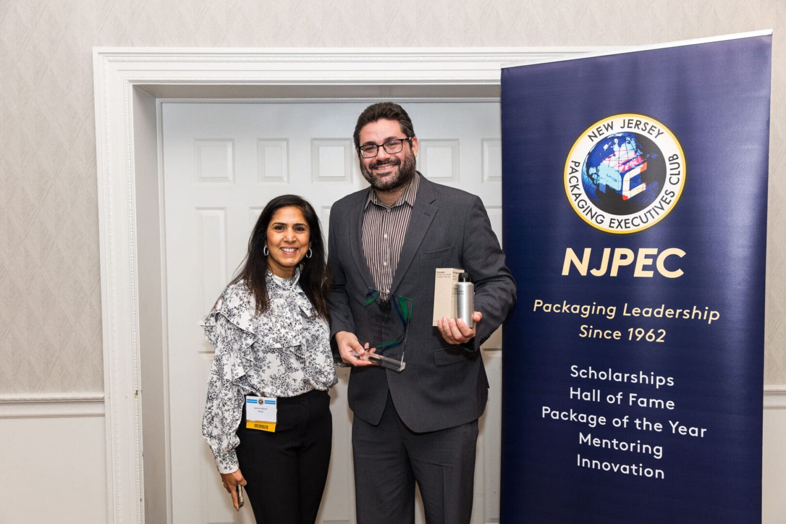 A man and woman standing in front of a sign that says npec.