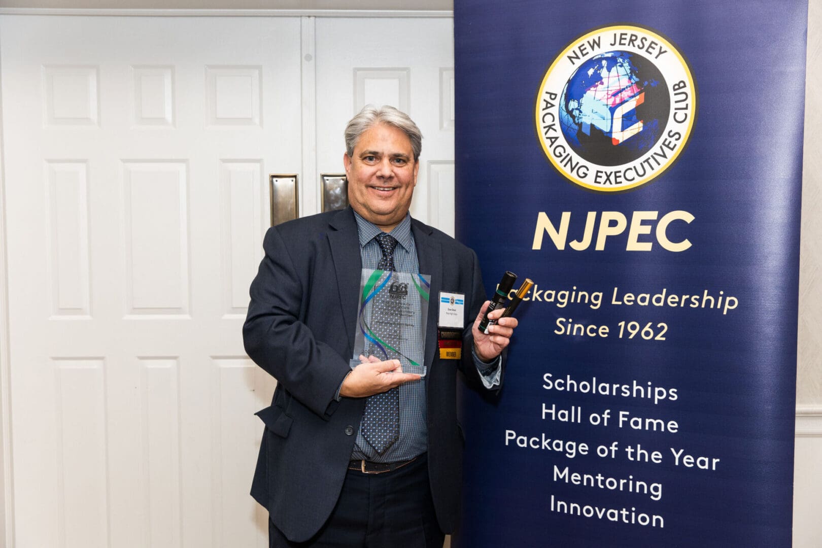 A man holding an award in front of a sign that says nipec.