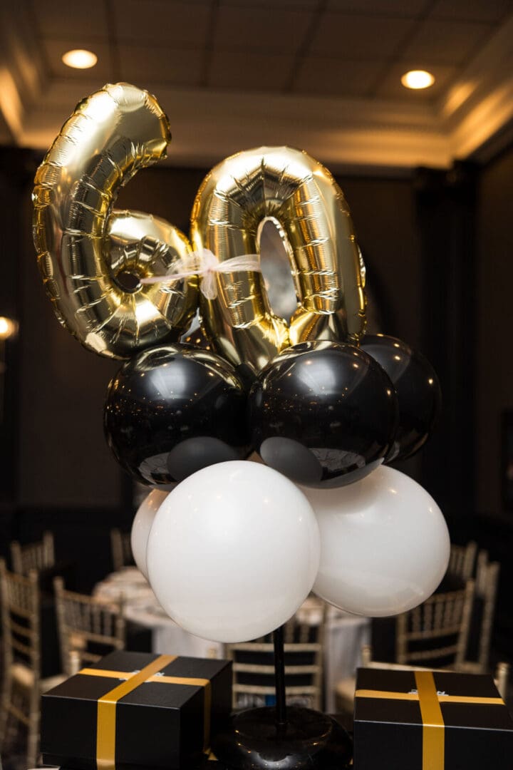 A 60th birthday balloon centerpiece with black and gold balloons.