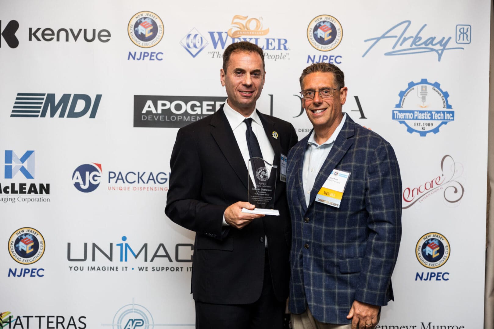 Two men in suits posing for a photo at an awards ceremony.