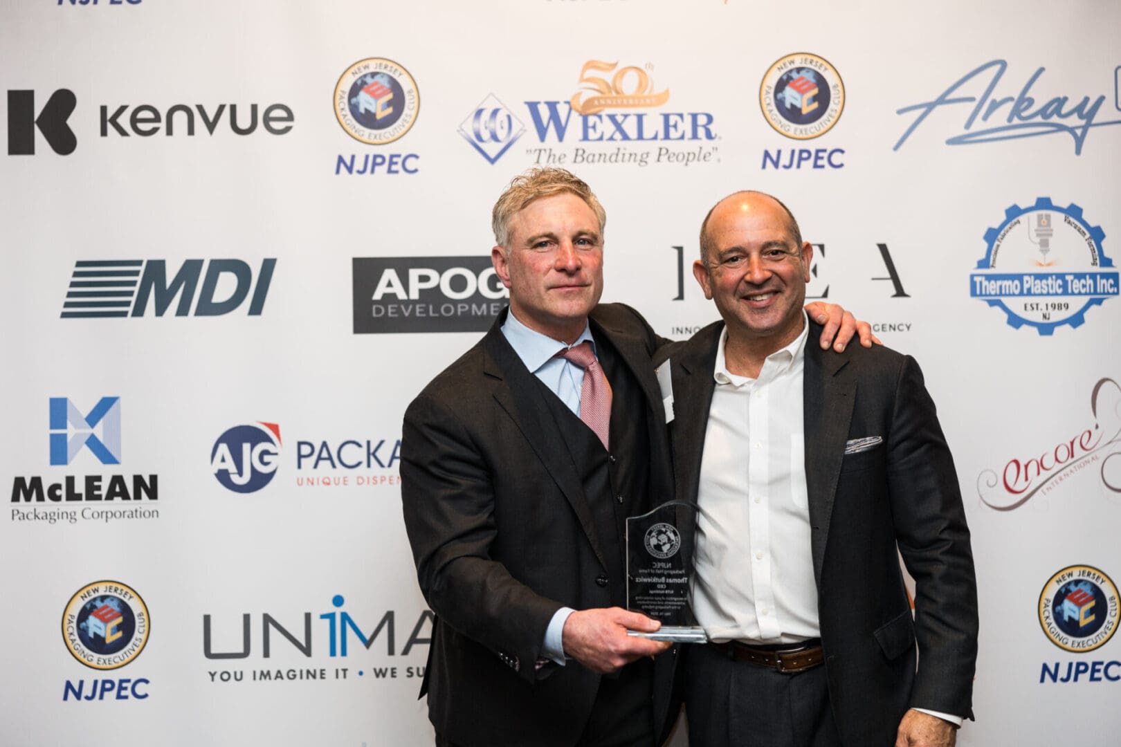 Two men in suits holding an award.
