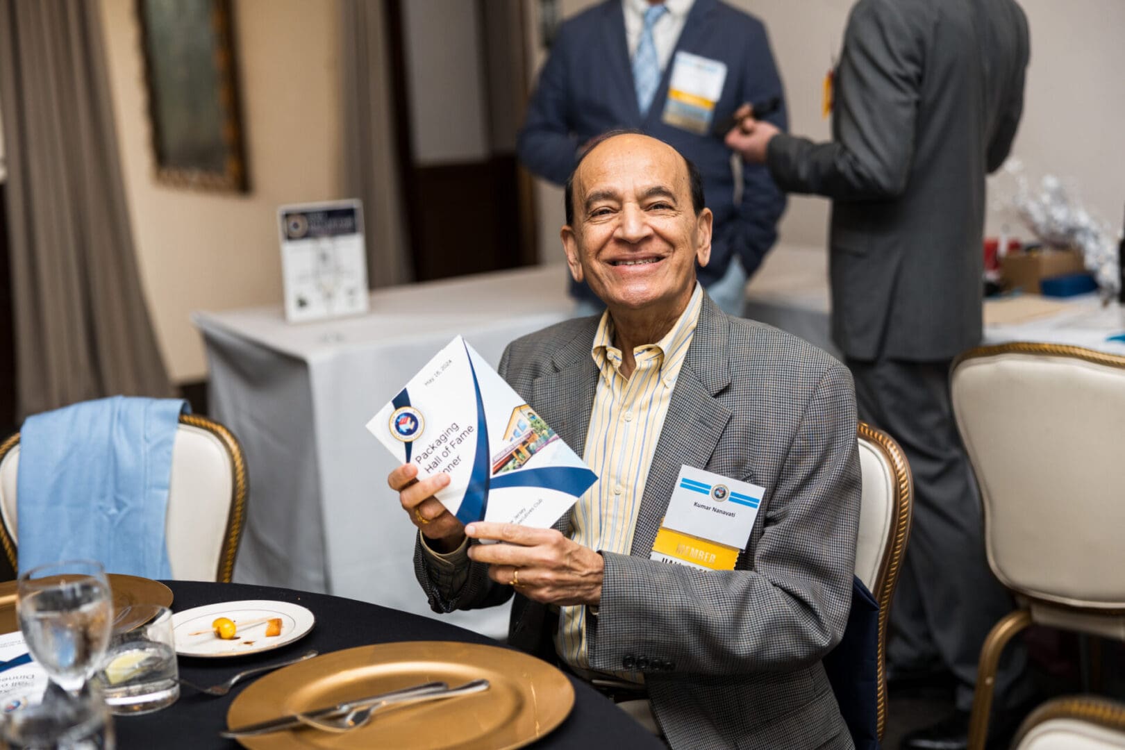 A smiling man holds a Packaging Hall of Fame booklet.