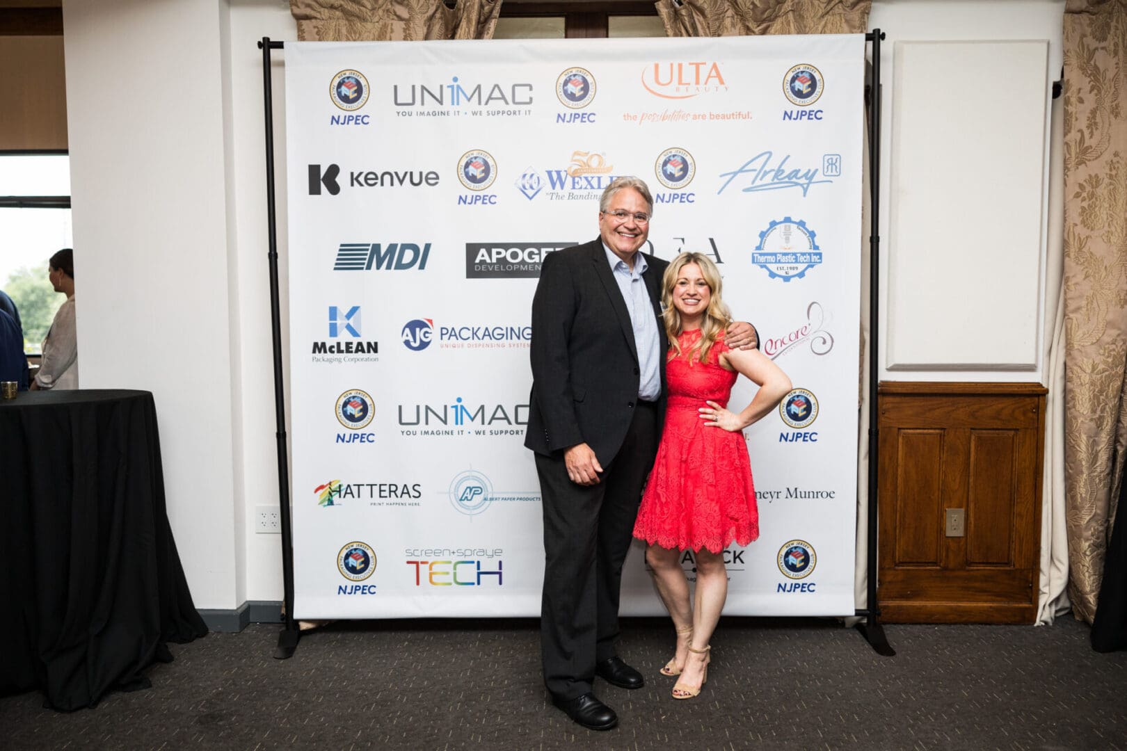 A man and a woman pose for a photo at an event.