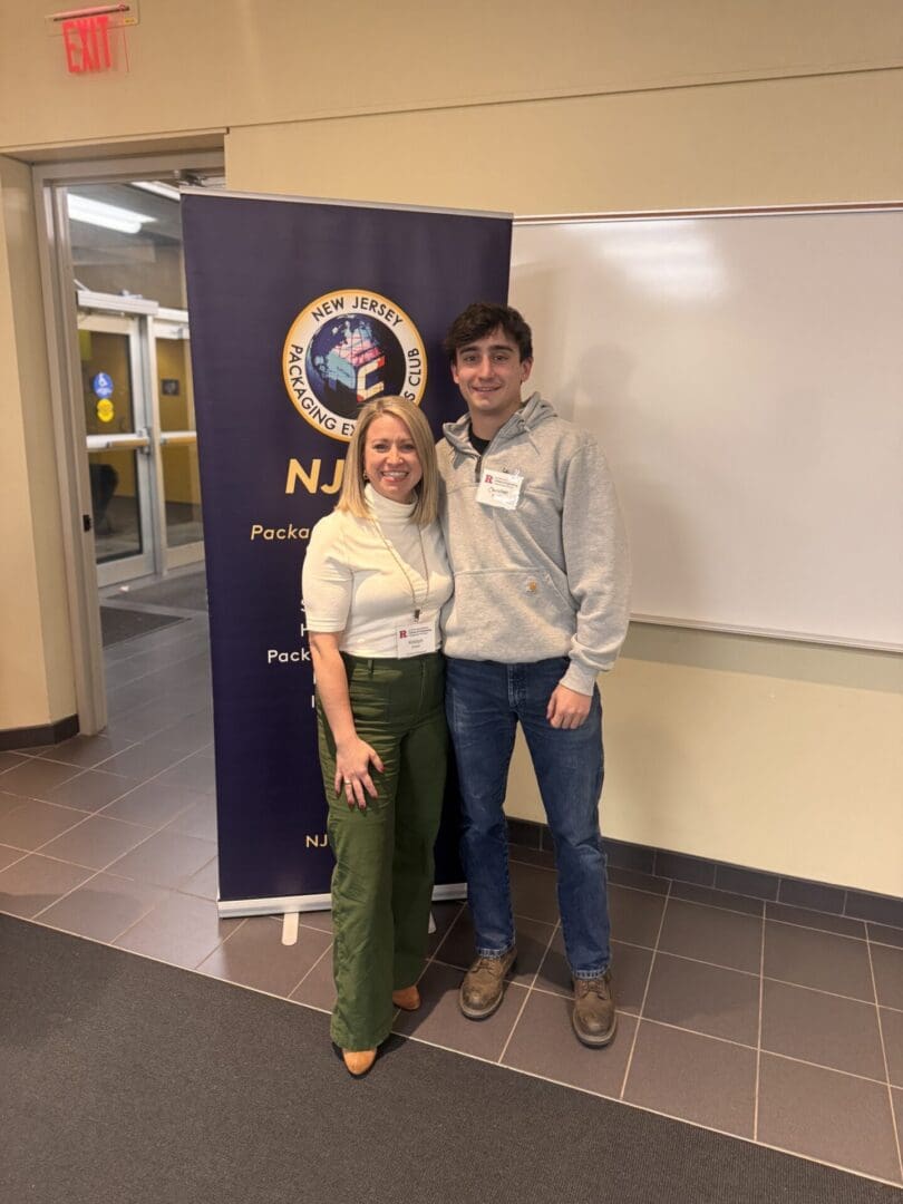 Two people standing by a conference banner.
