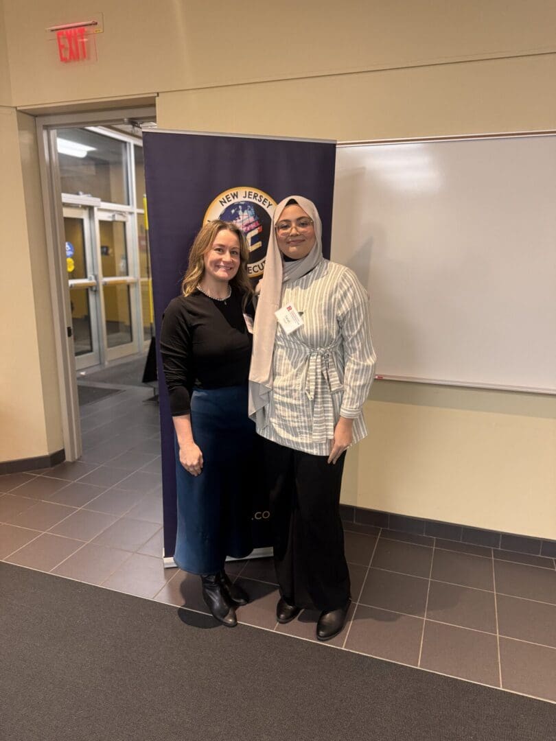 Two women posing in front of banner.