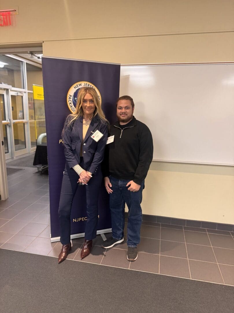Two people standing by a conference banner.